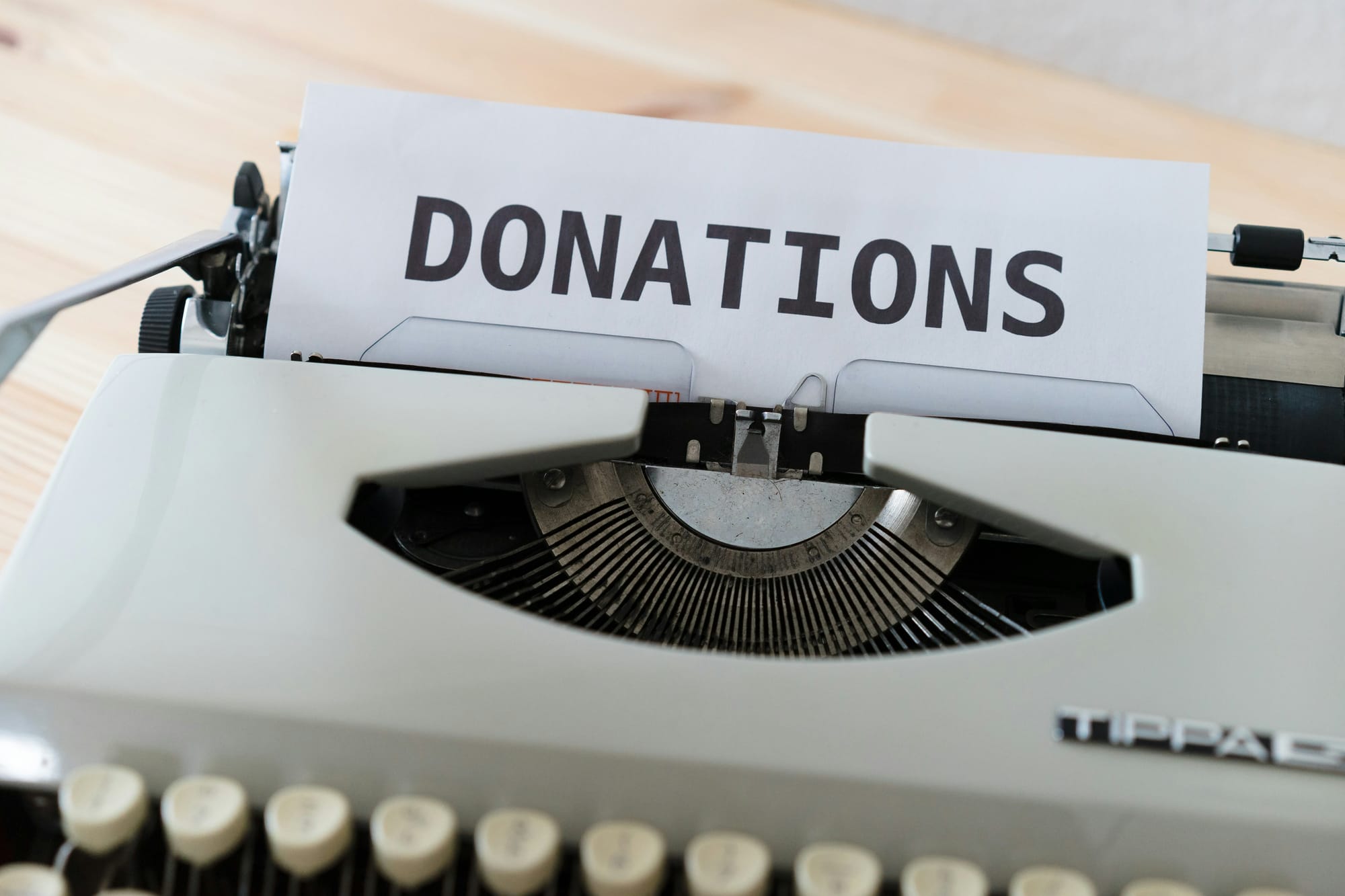 Manual typewriter with a sheet of paper rolled in reading DONATIONS in large letters